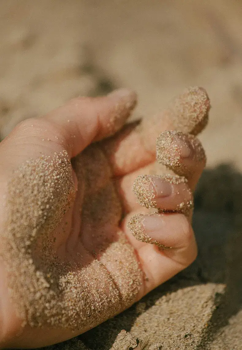 Hand resting in sand