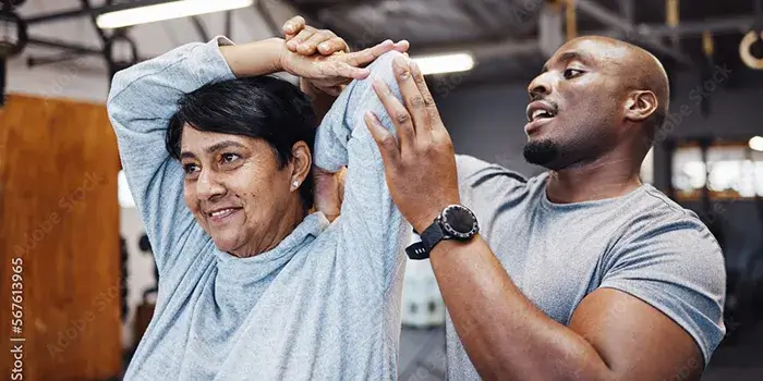 trainer helping woman stretch